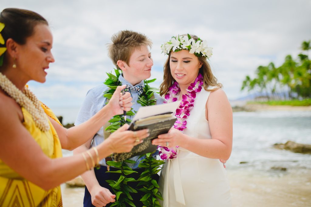 gay wedding hawaii, header (two women saying their wedding vows on the beach in front of a female officiant)